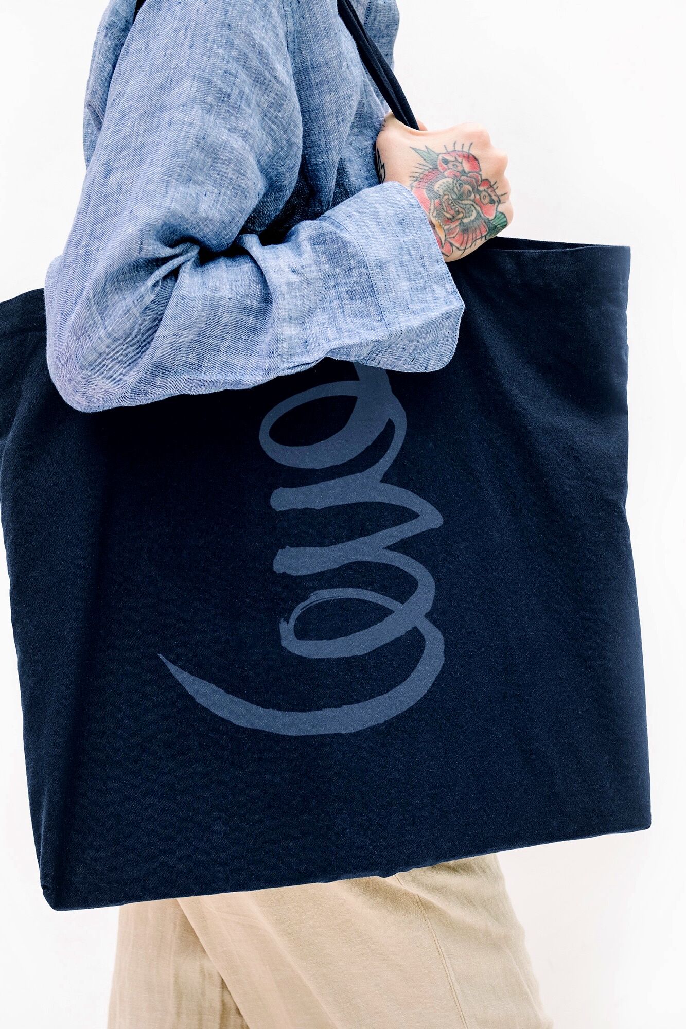 Tattooed Woman In A Blue Linen Shirt Holding A Black Tote Bag Mockup