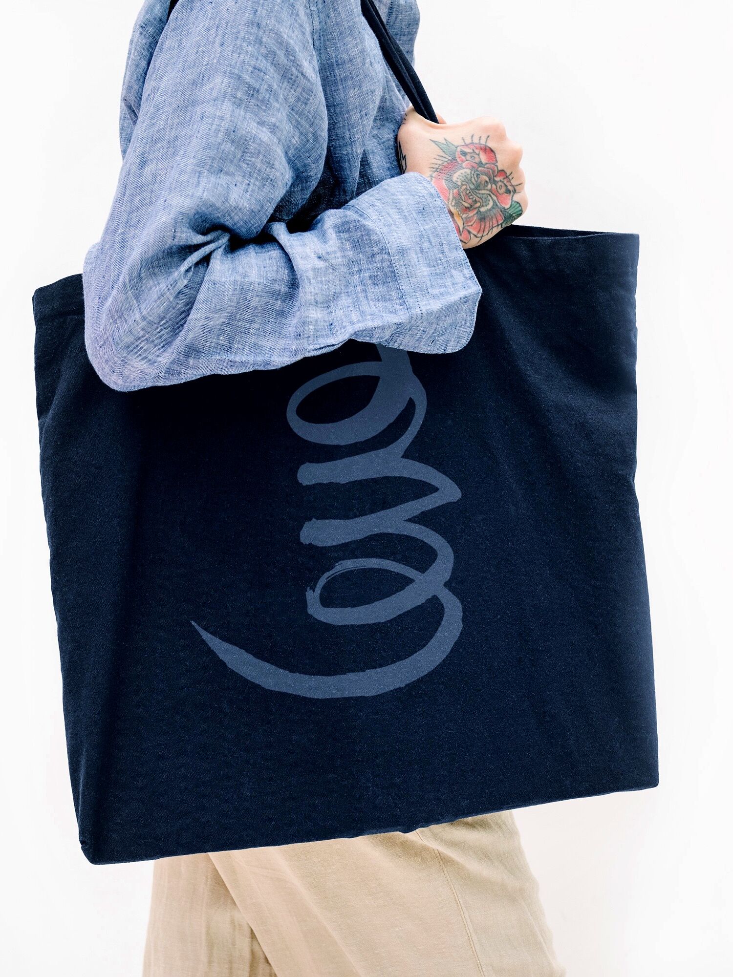 Tattooed Woman In A Blue Linen Shirt Holding A Black Tote Bag Mockup